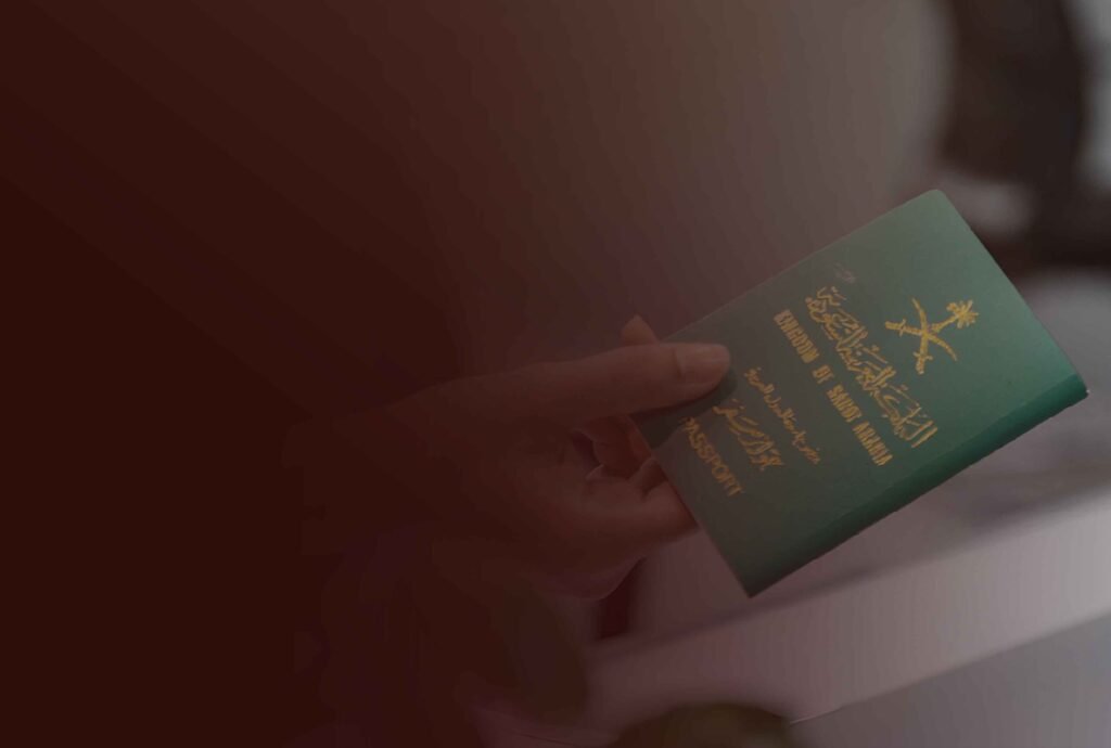 A hand holding a green Saudi Arabian passport